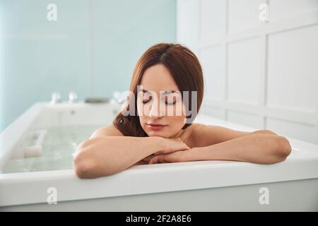 Peaceful woman laying head on her arms in jacuzzi Stock Photo