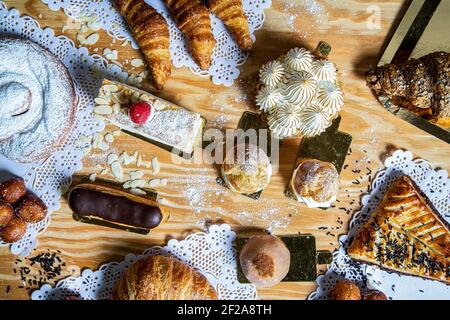 Top view of a variety of homemade cakes such as tarts, lemon pie, lionesses, mochi, croissant, eclair, sweet and delicious. Stock Photo