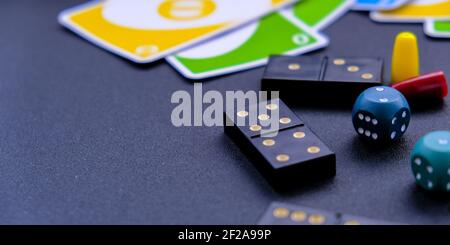Kiev Ukraine - 10.03.21 Dice, dominoes uno playing cards on black background. Table games. Stay home activity for kids family. Stock Photo
