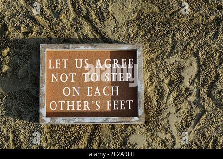 Text on wooden frame laying on sandy beach - Let us agree not to step on each other feet Stock Photo