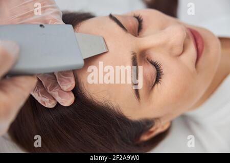 Charming woman receiving facial treatment at wellness center Stock Photo