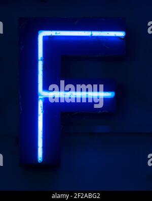 Blue shining neon letter F at night Stock Photo