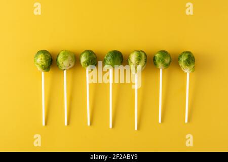 Set of brussel sprouts with lollipop sticks on yellow background Stock Photo