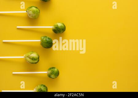 Set of brussel sprouts with lollipop sticks on yellow background Stock Photo