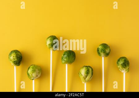 Set of brussel sprouts with lollipop sticks on yellow background Stock Photo