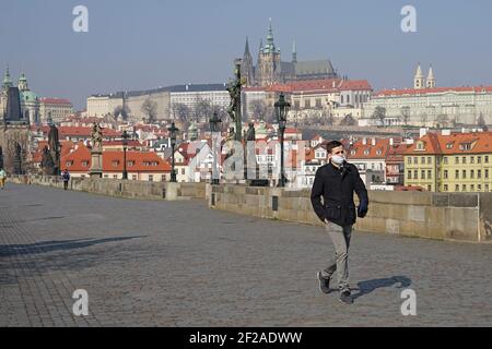 Prague, Czech Republic - March 20 2020: Coronavirus covid-19 picture of empty Charles Bridge with man wearing protecting mask Stock Photo