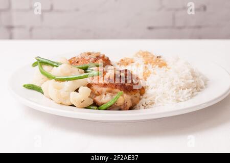 crispy fried chicken thighs with vegetables over rice in a lemon sauce Stock Photo