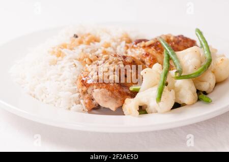 crispy fried chicken thighs with vegetables over rice in a lemon sauce Stock Photo