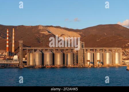 cisterns for storing grain in the port by the sea against the backdrop of the mountain Stock Photo