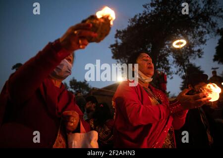 Kathmandu, Nepal. 11th Mar, 2021. Nepalese Hindu devotees offering butter lamps to the Lord Shiva at the Pashupatinath temple premises during a Mahashivaratri festival.Hindu Devotees from Nepal and India come to this temple to take part in the Shivaratri festival which is one of the biggest Hindu festivals dedicated to Lord Shiva and celebrated by devotees all over the world. Credit: SOPA Images Limited/Alamy Live News Stock Photo