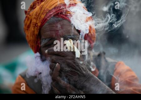 Kathmandu, Nepal. 11th Mar, 2021. A Hindu holy man, or sadhu, smokes marijuana at the Pashupatinath Temple during the Mahshivaratri festival in Kathmandu.Hindu Devotees from Nepal and India come to this temple to take part in the Shivaratri festival which is one of the biggest Hindu festivals dedicated to Lord Shiva and celebrated by devotees all over the world. Credit: SOPA Images Limited/Alamy Live News Stock Photo