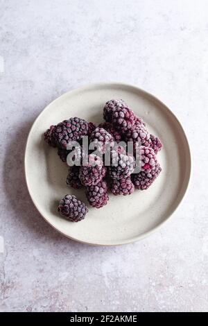 Small plate with frozen blackberries viewed from above. Stock Photo