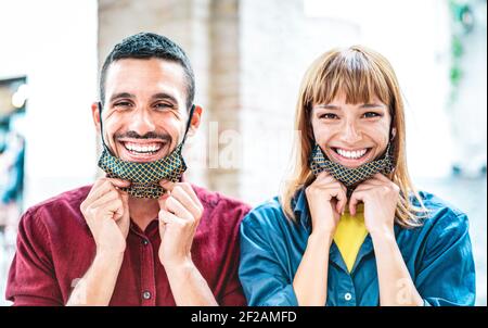 Happy couple in love smiling with open face mask - New normal lifestyle and relationship concept with young people on positive mood after lockdown Stock Photo