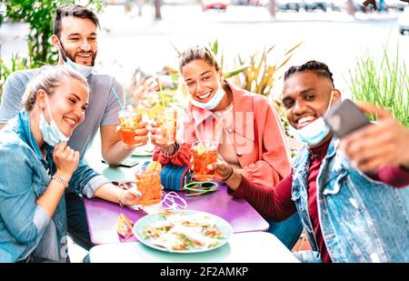 Multicultural people taking selfie with open face masks at cocktail bar - New normal life style concept with young friends having fun Stock Photo