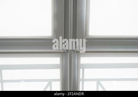 White fabric roller blinds on the plastic window on a balcony in the living room. Stock Photo
