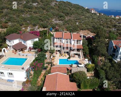 Beautiful summer house villa with three stories and pool under sunny bright blue clear skies surrounded with green natural healty plants. Stock Photo