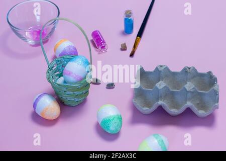 Wicker nest, basket with pink golden decorated eggs isolated on blue background. Ester banner greeting card, promotion flyer. Copy space, front view, Stock Photo