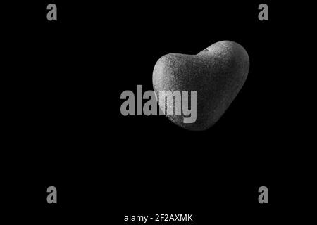 A heart-shaped stone in the air, black backround, black and white, heart shaped, rock heart, love is in the air, pebble heart, valentines day, 14th Fe Stock Photo