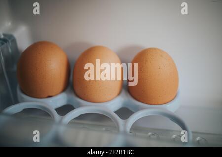 A close-up shot of three eggs on a white plastic stand. Stock Photo