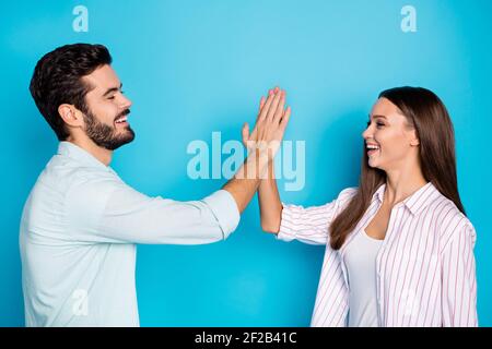 Photo of joyful happy attractive couple give each other high five relationship goals isolated on blue color background Stock Photo