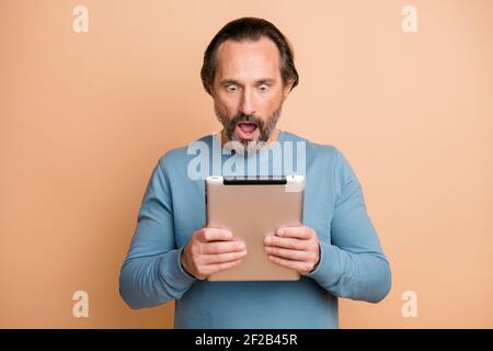 Photo portrait of shocked businessman reading fake news in internet keeping tablet isolated on pastel beige color background Stock Photo