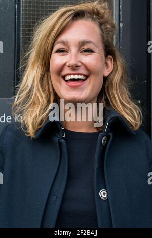 Amsterdam, Netherlands. Young adult causasian female standing at a building's door, to recieve and welcome guests and visitors. Stock Photo