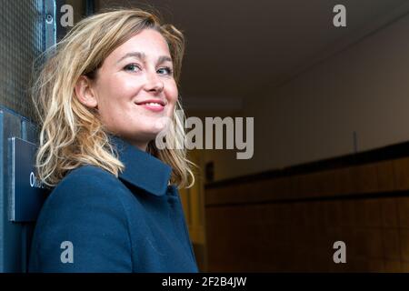 Amsterdam, Netherlands. Young adult causasian female standing at a building's door, to recieve and welcome guests and visitors. Stock Photo