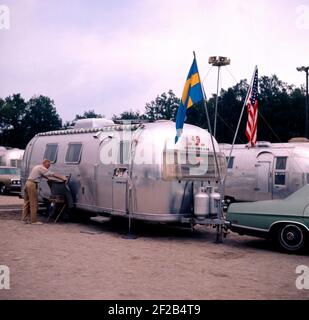1970s camping. Pictured an American Airstream caravan in aluminium and in the typical 1930s streamline design. The caravan was designed by Hawley Bowlus who was inspirered by the airplane Spirit of St. Louis. Around the world, owners of Airstream caravans meet and this picture was taken in Sweden on September 21 1971. Stock Photo