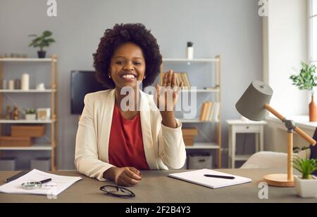 African american business woman waving in front of webcam welcoming online conference attendees. Stock Photo