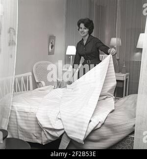 In the 1960s. A woman is making her bed with fresh sheets. Sweden 1960 ref CS12-5 Stock Photo