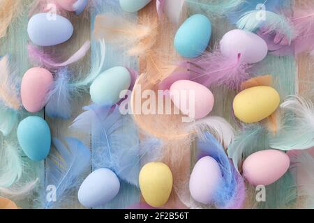 Happy easter concept. Colorful Easter eggs and feathers on wooden background. Flat lay. Stock Photo