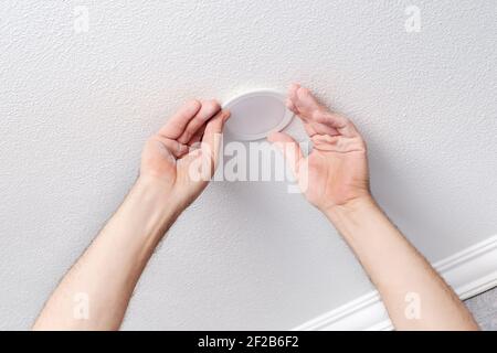 Electrician hands repairs or installs modern LED light bulb Stock Photo