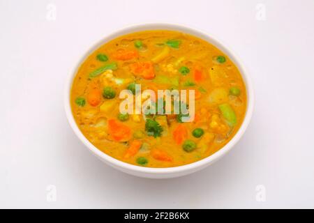 Mixed veg curry or kurma  tasty indian dish made of different vegetables like cauliflower, carrot, potato, green peas and garnished with onion pieces Stock Photo