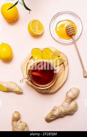 A cup of ginger tea, honey, lemon and ginger root, flat lay on a pink background. The modern wellness concept. Vegan, healthy food, boosting immunity. Stock Photo