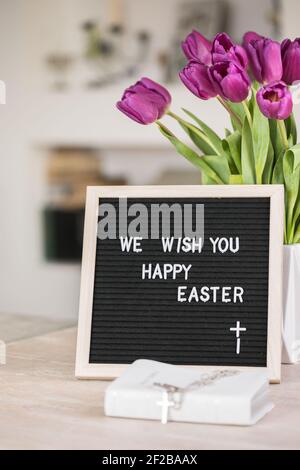 Spring concept. Bouquet of purple tulips flowers and letter board with the words We wish you  happy Easter. Happy Easter greeting card, gift, poster, Stock Photo