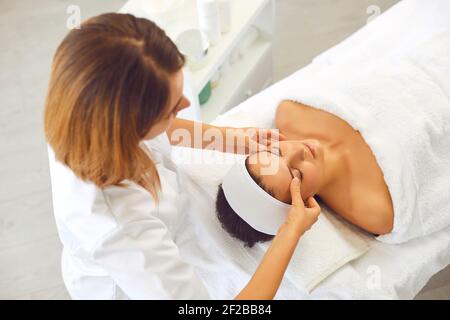 Cosmetologist making revitalizing lifting facial massage for young woman Stock Photo