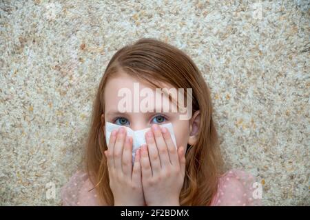 Child girl with a cold virus wipes his nose from a runny nose