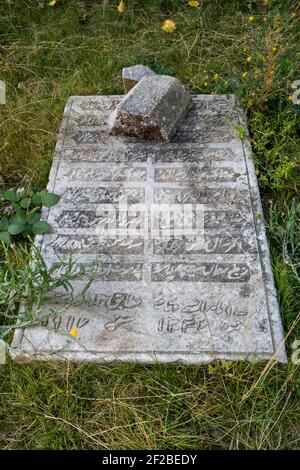 SHUSHI, NAGORNO KARABAKH - NOVEMBER 03: A smashed headstone of a muslimi grave at the courtyard of the 18th century Yukhari Govhar Agha Mosque which also bears the name Boyuk Juma (Great Mosque) in the town of Shushi or Shusha in the self-proclaimed Republic of Artsakh or Nagorno-Karabakh, de jure part of the Republic of Azerbaijan on November 03 2020. Stock Photo