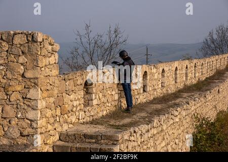 SHUSHI, NAGORNO KARABAKH - NOVEMBER 03: A journalist filming from the castle walls of the 18th century fortress in the town of Shushi or Shusha during a military conflict between Armenian and Azerbaijani forces over the disputed Nagorno-Karabakh region known also as the Artsakh Republic on November 03 2020. The fighting between Armenia and Azerbaijan over Nagorno-Karabakh known also as the Artsakh Republic re-erupted in late September into a six-week war with both countries accusing each other of provocation that left thousands dead. Stock Photo