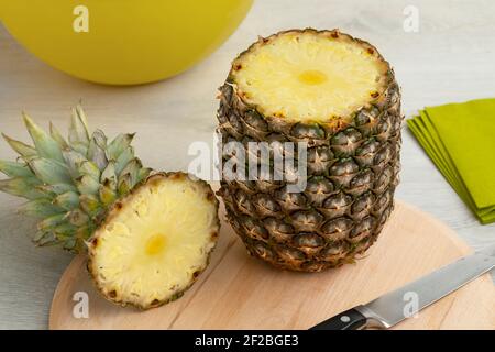 Fresh raw ripe tropical pineapple on a cuttingboard with a cut top Stock Photo
