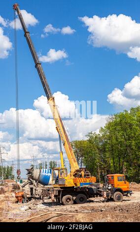 Samara, Russia - May 7, 2016: Truck crane and concrete mixer truck working at the construction site in summer Stock Photo