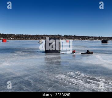 Barrie, Ontario, Canada - March 7, 2021: Ice fishing tents on frozen blue ice of Kempenfelt Bay on Lake Simcoe in winter Stock Photo