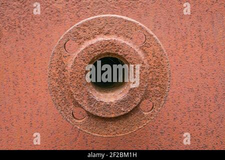 rusty element of the old construction hole is overgrown with cobwebs. The spare part. Round iron disk with screw cuts. Stock Photo