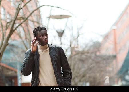 A young Afro-American guy talking on the phone in the streets of Lyon in France Stock Photo