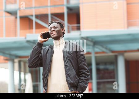 A cheerful young Afro-American guy talking on the phone in the streets of Lyon in France Stock Photo