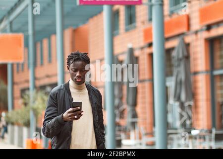 A young Afro-American guy using his phone in the streets of Lyon i France Stock Photo