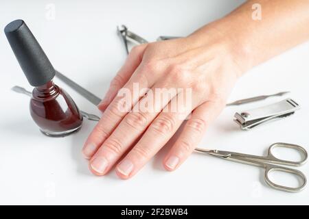 Manicure tools and female hand on white background. Making self-manicure at home concept. Stock Photo