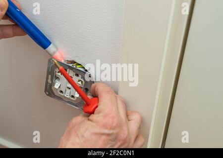 Сlose up view of man checks voltage in the electrical outlet. Sweden. Stock Photo
