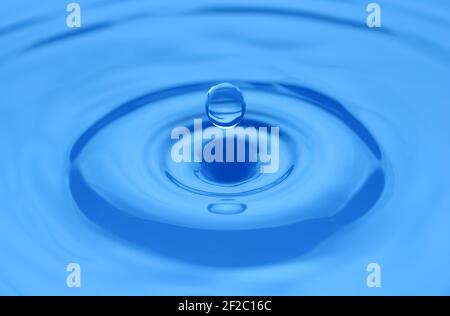 Water drop close up on a blue surface. Abstract backgrpound. Shallow DOF. Concept of meditation and harmony. Stock Photo