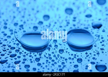 Two contact lenses with drops on light background. Blue toned image. Concept correction vision. Stock Photo